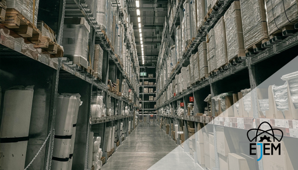 Corredor de armazém industrial com prateleiras altas repletas de materiais diversos, representando o armazenamento e a logística na seleção de materiais.